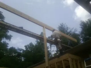 Carpenter setting a ridge beam over a new addition frame — Ice Dam Removal by Roofing Brothers in Phil Campbell