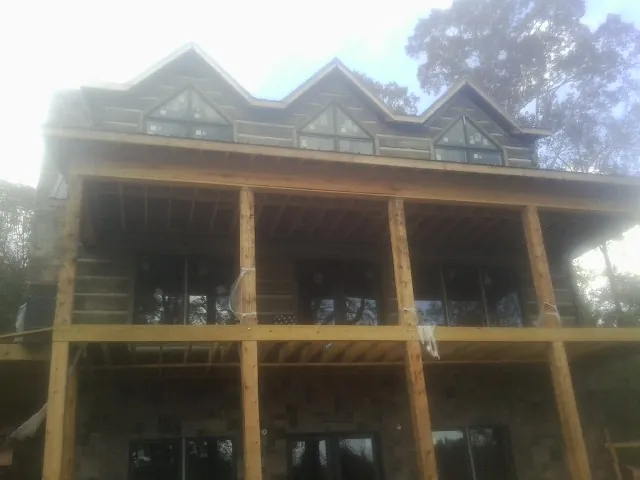 Dormers and porch framing on a large log home under construction — Roof Coating work by our crew in Phil Campbell