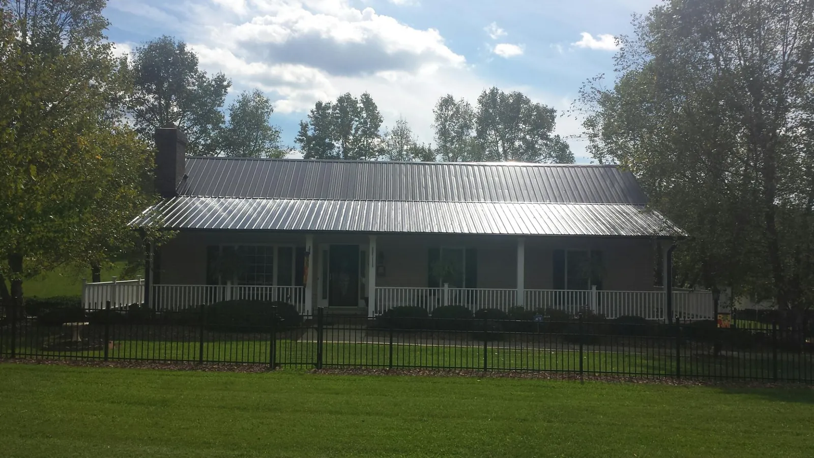 Gray metal roof on a brick ranch with a full width front porch — Gutter Guard Installation work by our crew in Phil Campbell