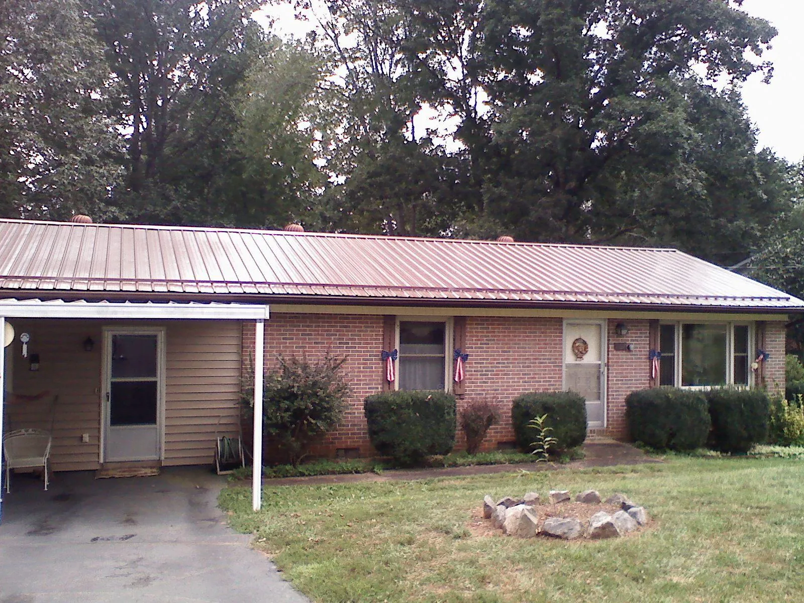 Bronze metal roof and carport on a brick ranch home — Roof Repair work by our crew in Phil Campbell