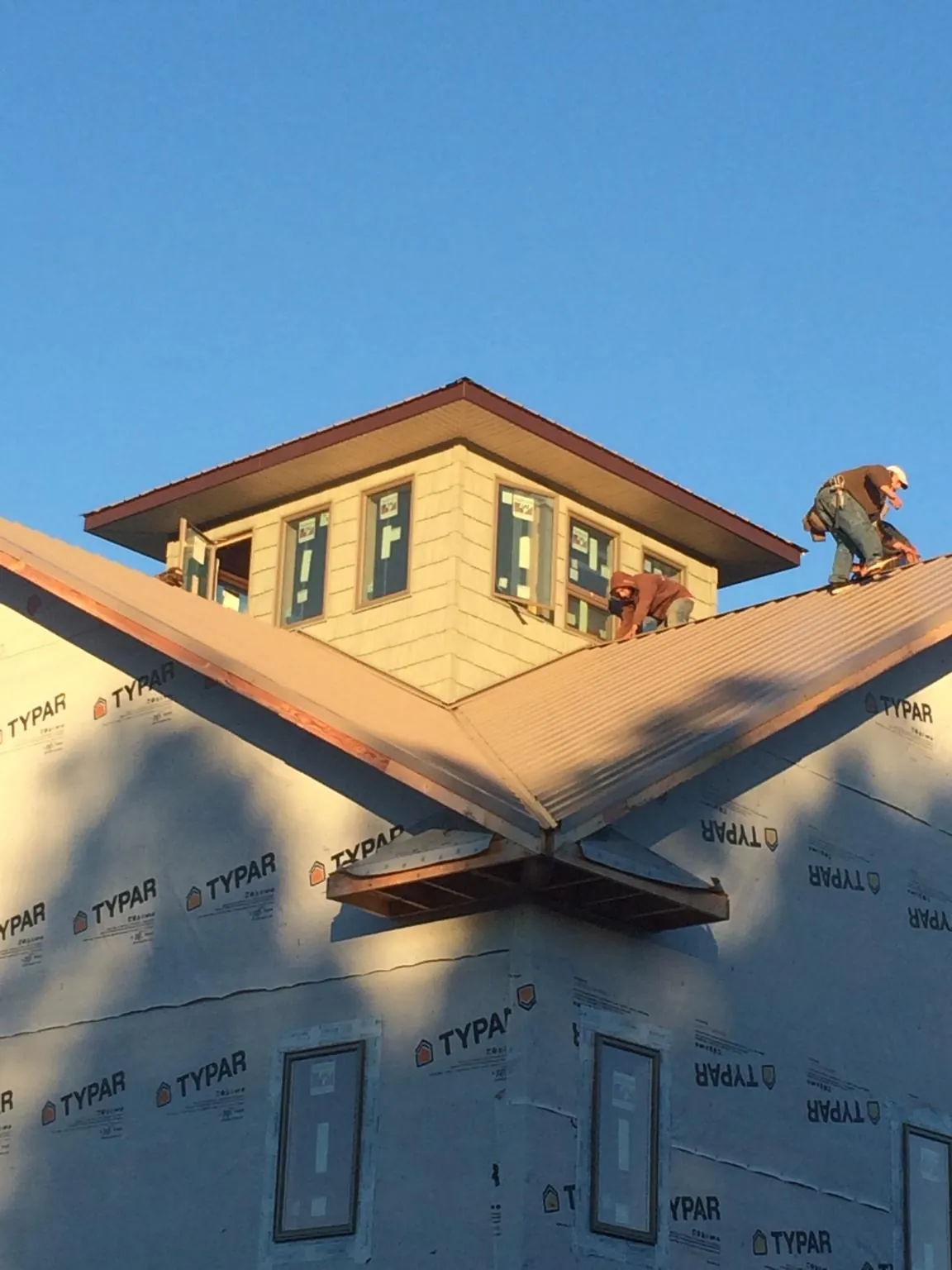 Roofers working around a rooftop cupola on a new metal roof at sunset — Roof Waterproofing in Phil Campbell by Roofing Brothers